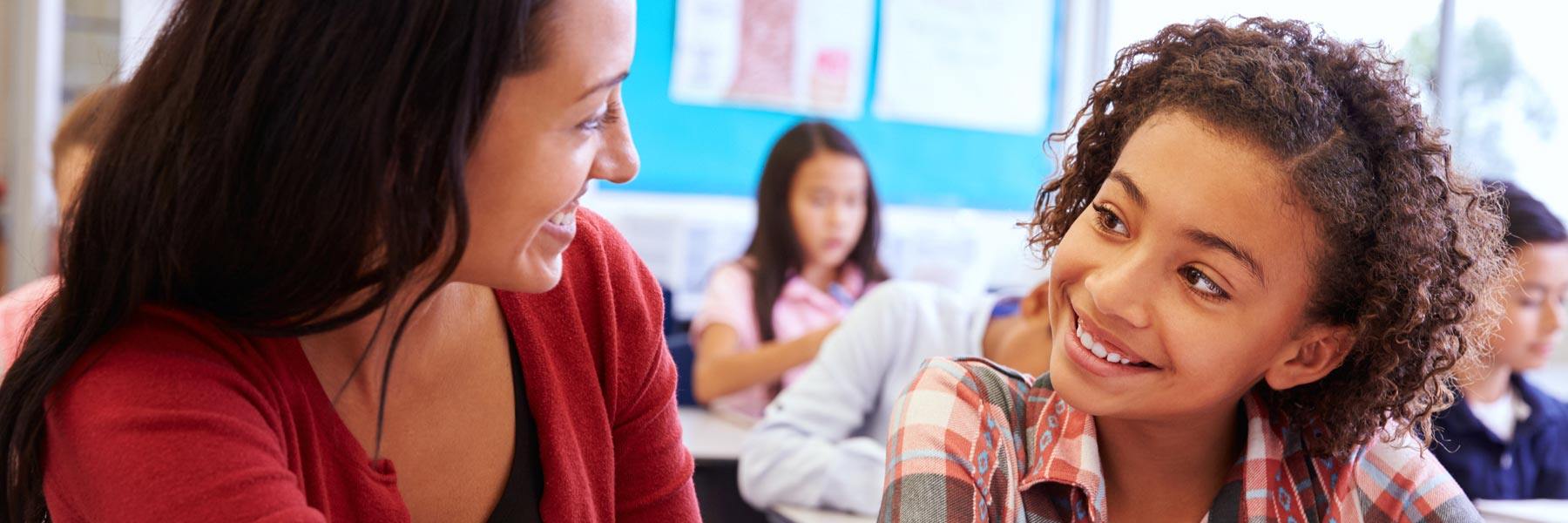 A teacher works one-on-one with a child in a classroom.