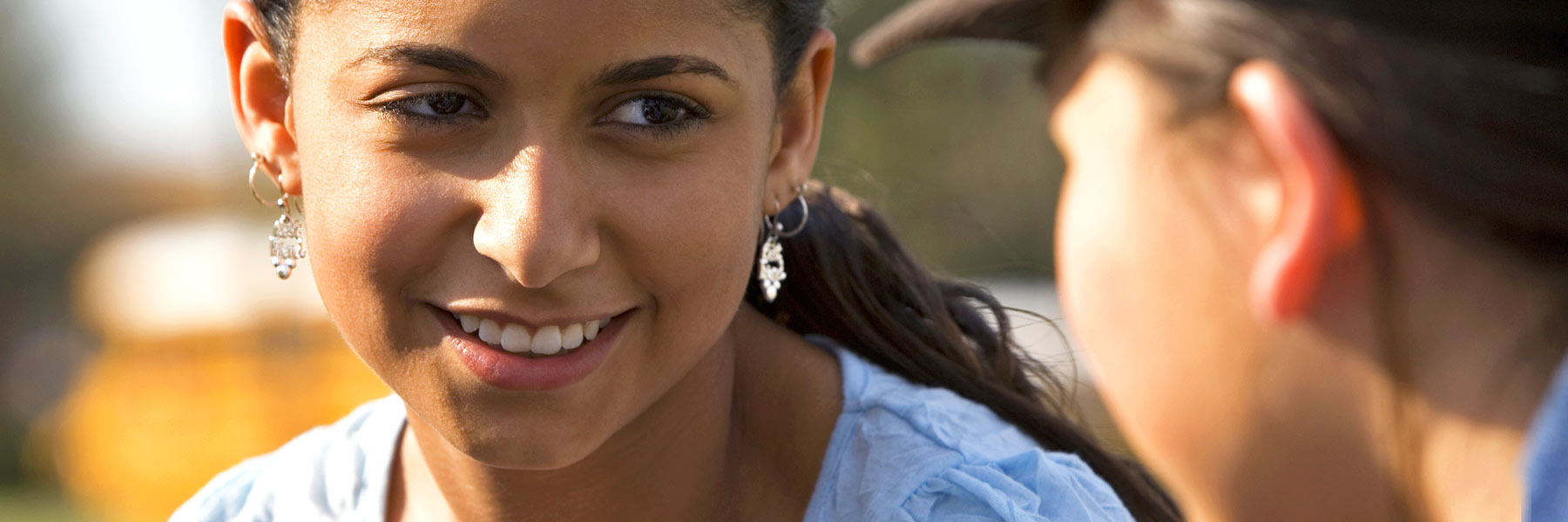 Two students sit and talk outside. 