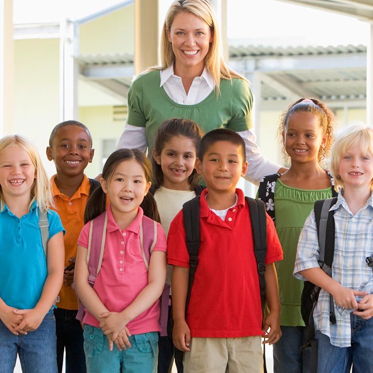 A teacher poses with a group of young students.