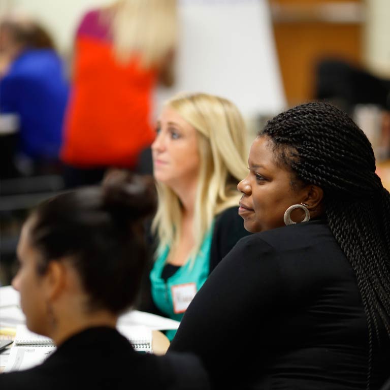 Three participants listen intently to a PBIS workshop presentation