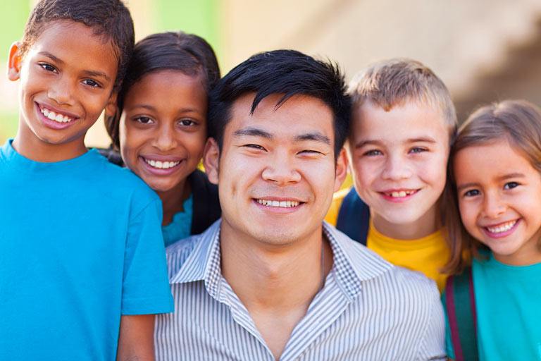 A teacher poses with four children.