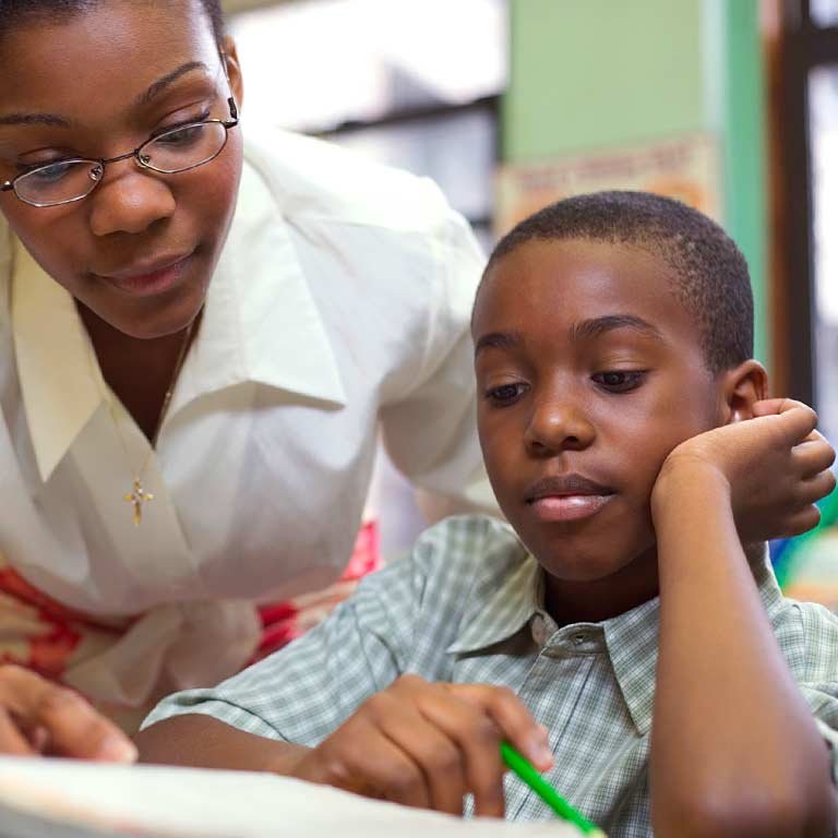A teacher assists a young student with a school lesson.